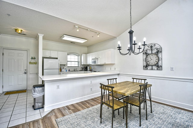 dining area featuring a chandelier, a textured ceiling, track lighting, and light wood-type flooring