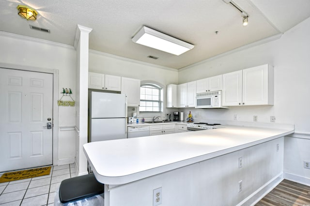 kitchen with crown molding, white cabinetry, track lighting, white appliances, and kitchen peninsula