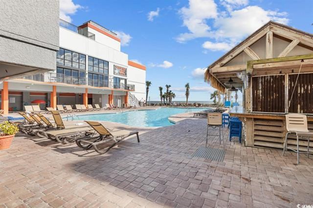 view of swimming pool featuring a patio and an outdoor bar