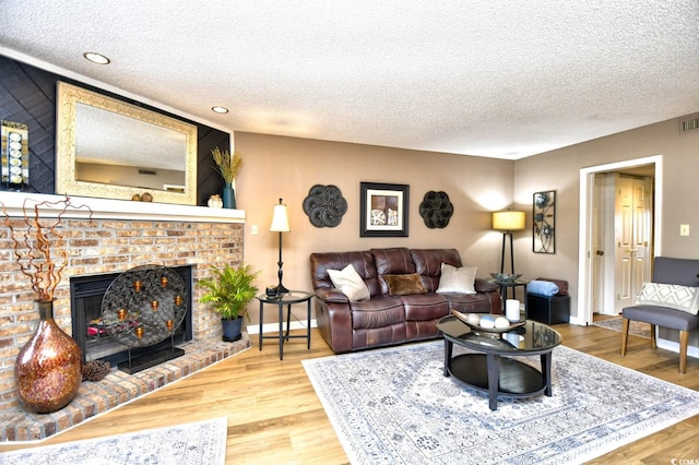 living room featuring a brick fireplace, hardwood / wood-style flooring, and a textured ceiling