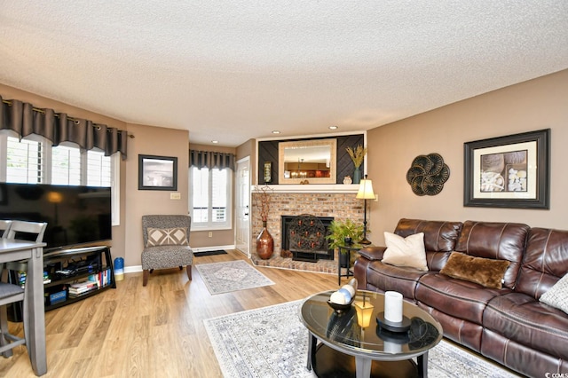 living room with a brick fireplace, hardwood / wood-style floors, and a textured ceiling