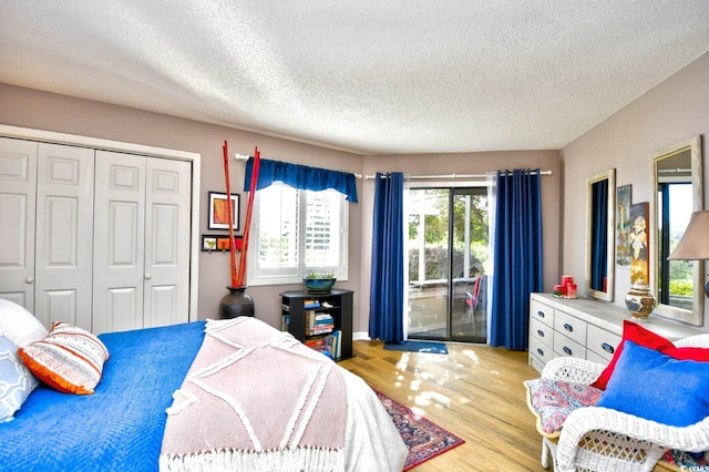 bedroom with a textured ceiling, a closet, light hardwood / wood-style flooring, and access to outside