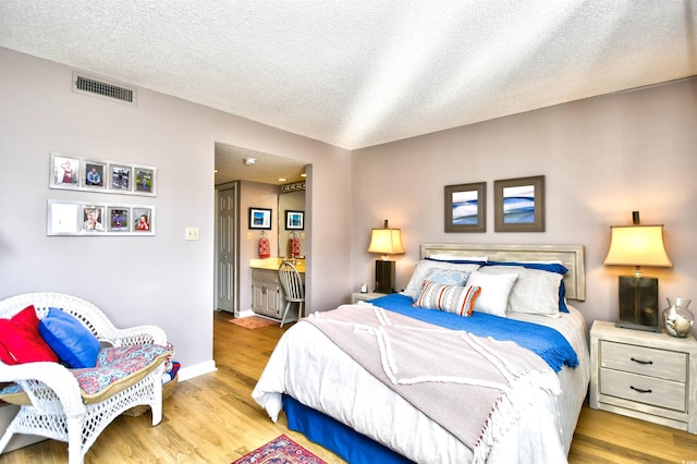 bedroom with light hardwood / wood-style floors and a textured ceiling