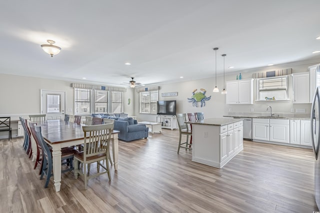 dining room with crown molding, ceiling fan, sink, and light hardwood / wood-style flooring