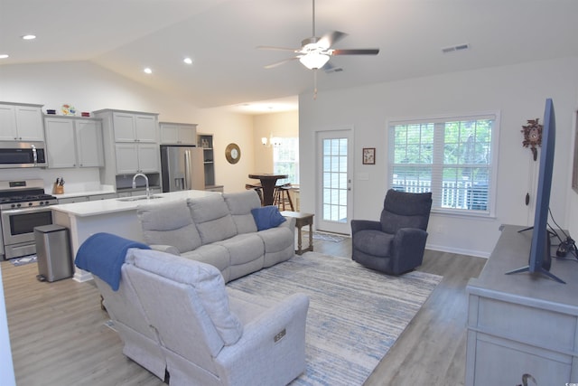 living room featuring sink, light wood-type flooring, vaulted ceiling, and ceiling fan