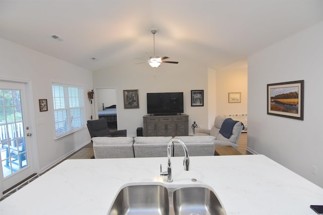 kitchen with light stone countertops, sink, hardwood / wood-style flooring, lofted ceiling, and ceiling fan