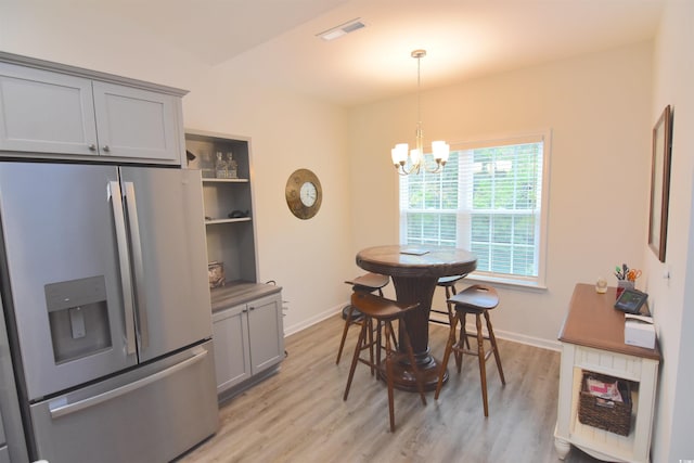 dining room with light hardwood / wood-style flooring and a notable chandelier