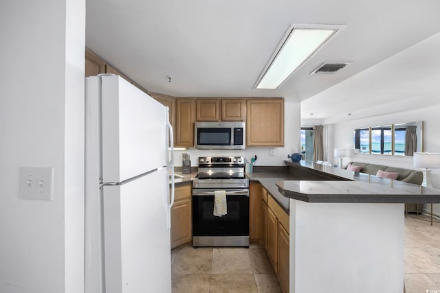 kitchen featuring stainless steel appliances, light tile patterned floors, and kitchen peninsula