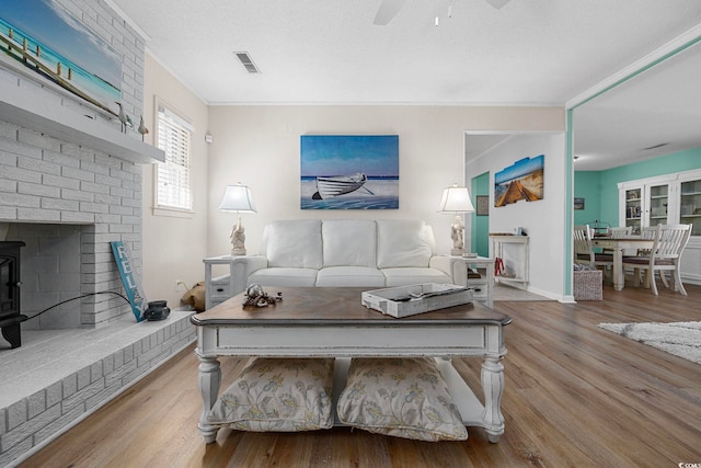 living room featuring light hardwood / wood-style floors, ceiling fan, a textured ceiling, and ornamental molding