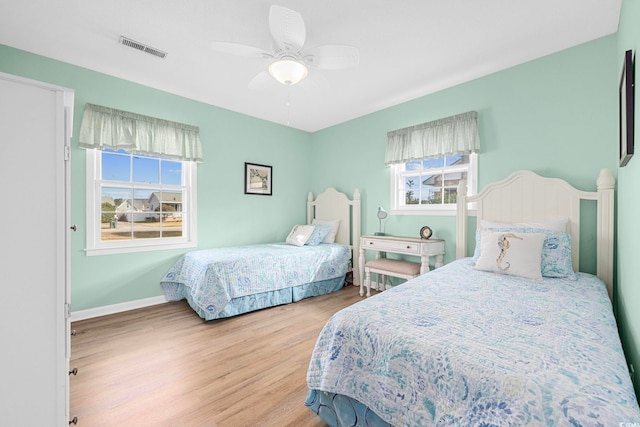 bedroom with light wood-type flooring, multiple windows, and ceiling fan