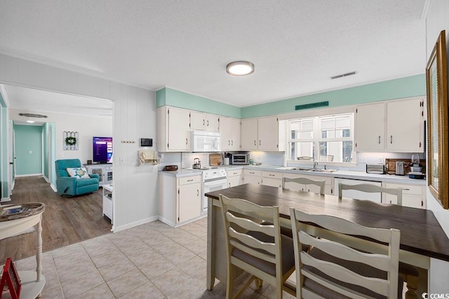 kitchen with white cabinetry, white appliances, and a textured ceiling