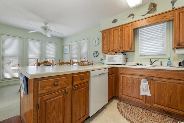 kitchen featuring white appliances, a textured ceiling, and kitchen peninsula