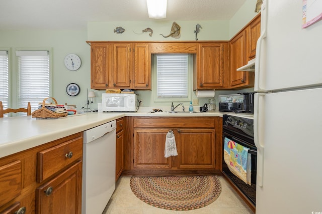 kitchen featuring a textured ceiling, sink, white appliances, and light tile patterned floors