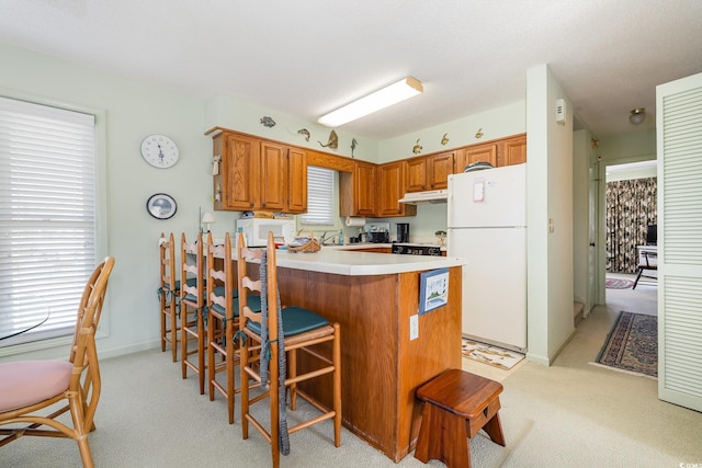 kitchen featuring white appliances, a breakfast bar area, light carpet, and kitchen peninsula