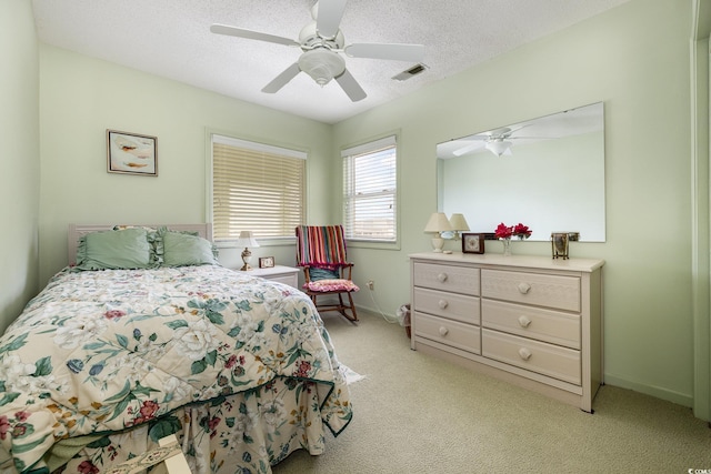 bedroom featuring a textured ceiling, light colored carpet, and ceiling fan