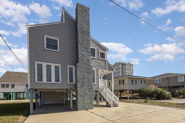 206 56th Ave N, North Myrtle Beach, SC 29582 - view of front facade with an attached garage, driveway, stairway, and a chimney