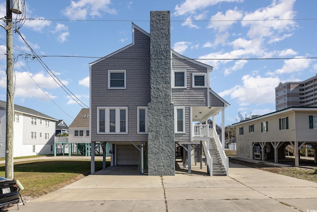 206 56th Ave N, North Myrtle Beach, SC 29582 - view of front of home with stairway, concrete driveway, a garage, covered porch, and a chimney
