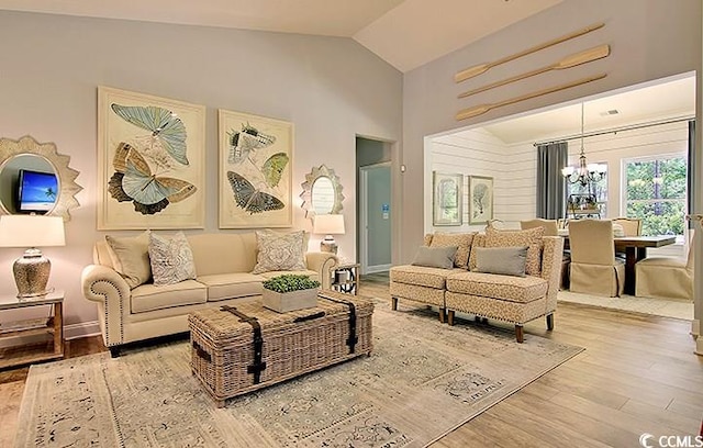 living room with hardwood / wood-style floors, an inviting chandelier, and vaulted ceiling