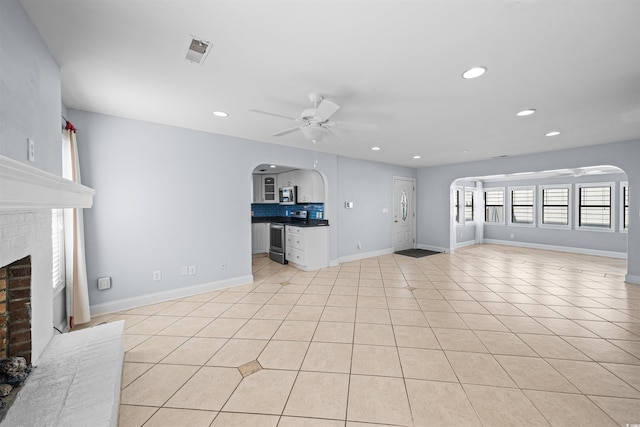 unfurnished living room featuring ceiling fan, a fireplace, and light tile patterned floors