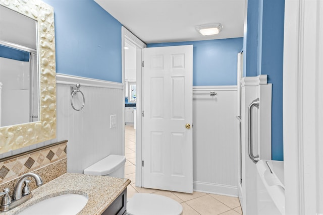 bathroom with tile patterned flooring, vanity, toilet, and walk in shower