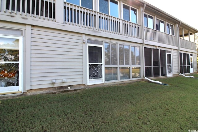 rear view of house with a balcony and a lawn