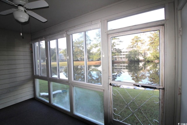 doorway with wood walls, ceiling fan, and a water view