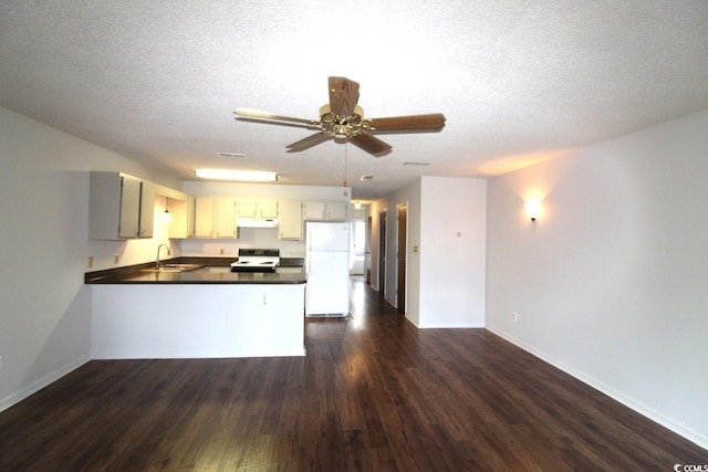 kitchen with sink, kitchen peninsula, dark hardwood / wood-style floors, a textured ceiling, and white appliances