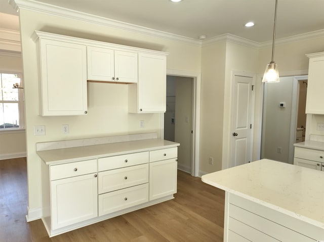 kitchen with light stone counters, ornamental molding, pendant lighting, light hardwood / wood-style flooring, and white cabinets