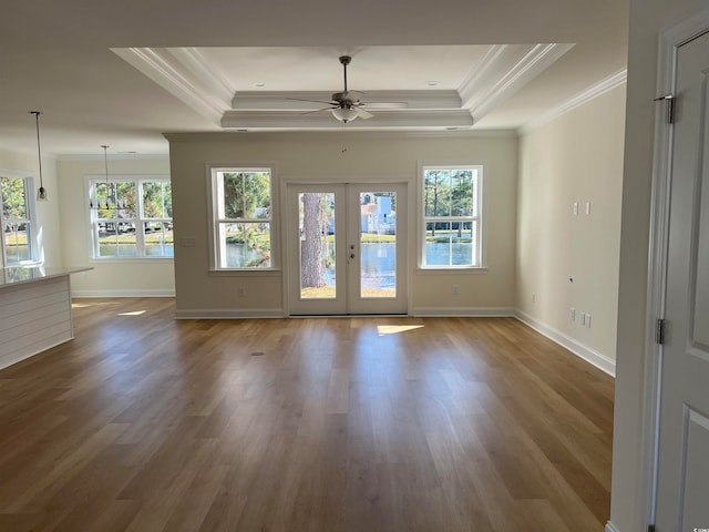 unfurnished room featuring french doors, a raised ceiling, ornamental molding, and wood-type flooring