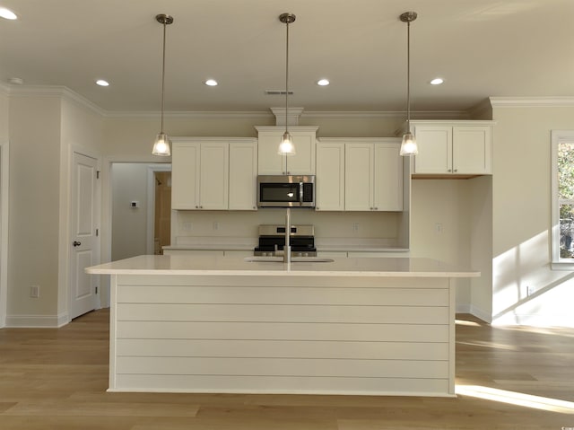 kitchen with a kitchen island with sink, hanging light fixtures, sink, light hardwood / wood-style floors, and stainless steel appliances