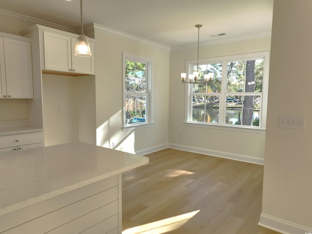 kitchen with white cabinets, light wood-type flooring, light stone countertops, and a healthy amount of sunlight