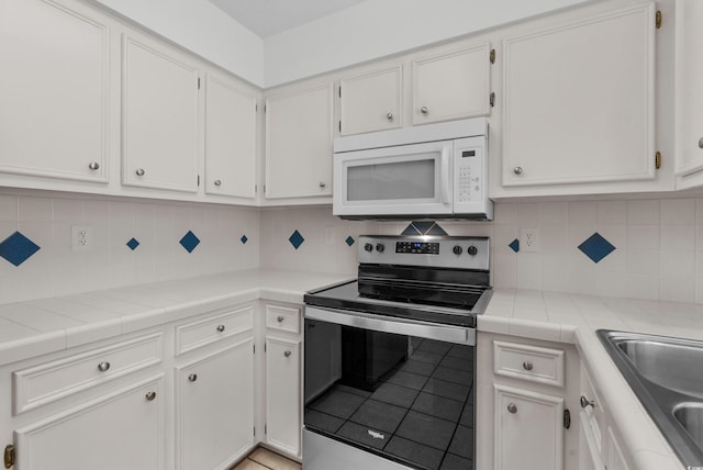 2925 Carriage Row Ln Unit 134, Myrtle Beach, SC 29577 - kitchen featuring white microwave, electric range, white cabinetry, light tile patterned floors, and backsplash