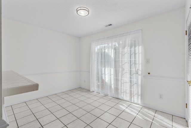 empty room with a textured ceiling and light tile patterned flooring