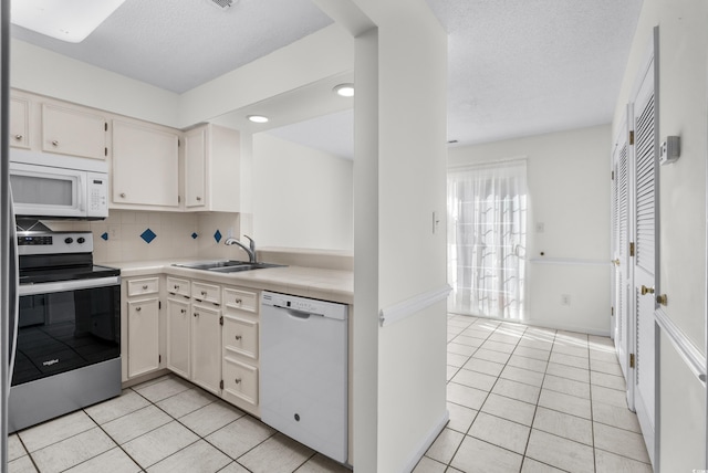 kitchen with a textured ceiling, tasteful backsplash, sink, light tile patterned floors, and white appliances