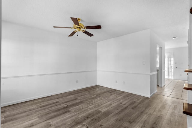 spare room featuring dark wood-type flooring, ceiling fan, and a textured ceiling