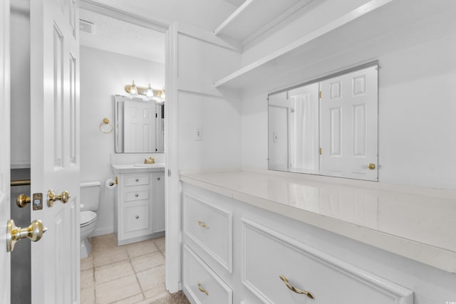 bathroom with toilet, vanity, and tile patterned floors