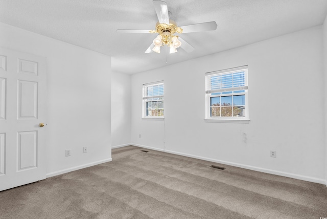 spare room with ceiling fan, a textured ceiling, and light colored carpet