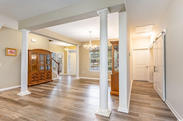 interior space with a barn door, an inviting chandelier, and light wood-type flooring