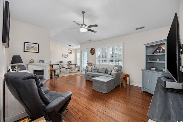 living room with wood-type flooring, vaulted ceiling, a textured ceiling, and ceiling fan