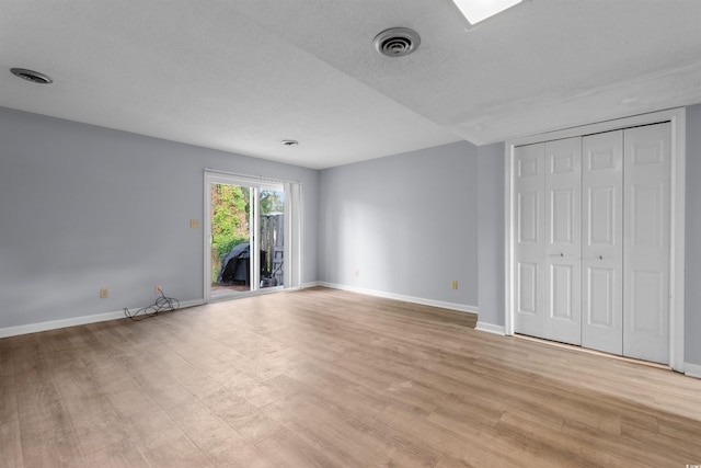 unfurnished bedroom with access to outside, a textured ceiling, and light wood-type flooring