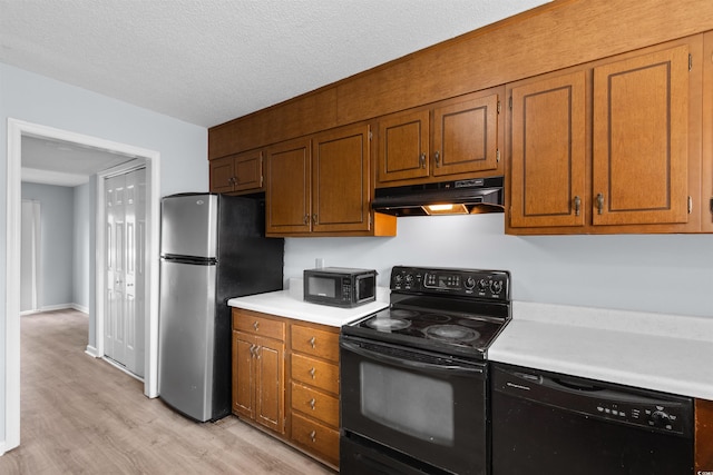 kitchen with black appliances, a textured ceiling, and light hardwood / wood-style flooring