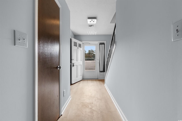 hallway with light wood-type flooring and a textured ceiling