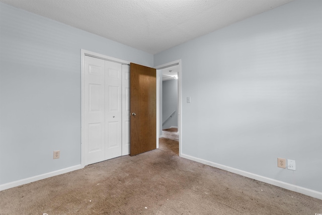 unfurnished bedroom with carpet, a textured ceiling, and a closet