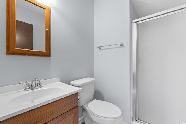 bathroom featuring a textured ceiling, vanity, an enclosed shower, and toilet