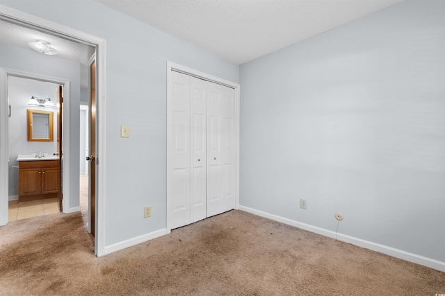 unfurnished bedroom with light carpet, ensuite bath, a closet, and sink