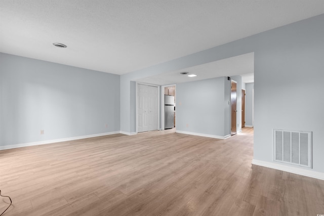 unfurnished room featuring a textured ceiling and light hardwood / wood-style flooring