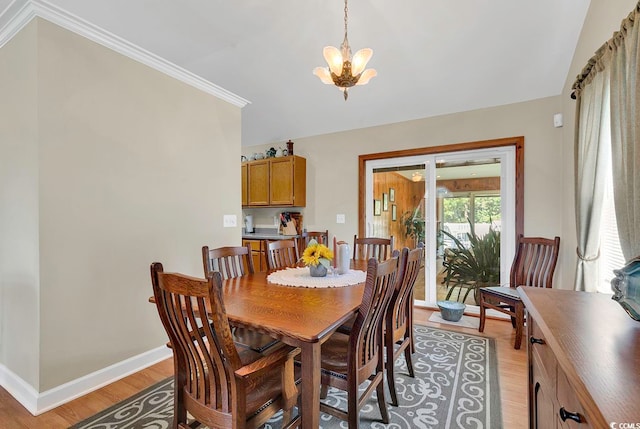 dining room featuring an inviting chandelier, light hardwood / wood-style flooring, and crown molding