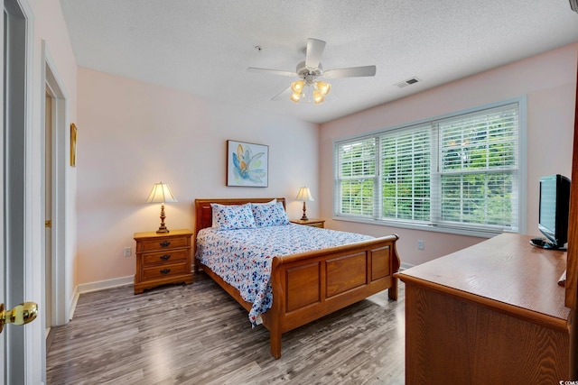 bedroom featuring ceiling fan, wood-type flooring, and multiple windows