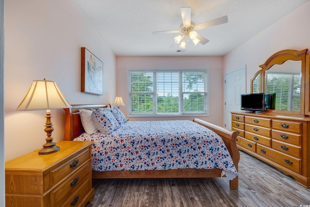 bedroom with multiple windows, ceiling fan, a textured ceiling, and hardwood / wood-style flooring