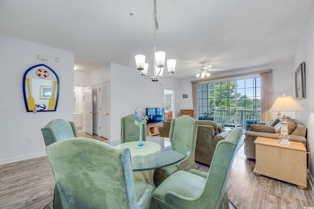 dining area with ceiling fan with notable chandelier and light hardwood / wood-style floors